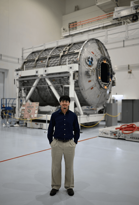 Pablo standing in front of a large cylindrical spacecraft structure.